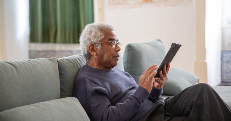 Senior man reading on tablet while receiving home care in Toronto